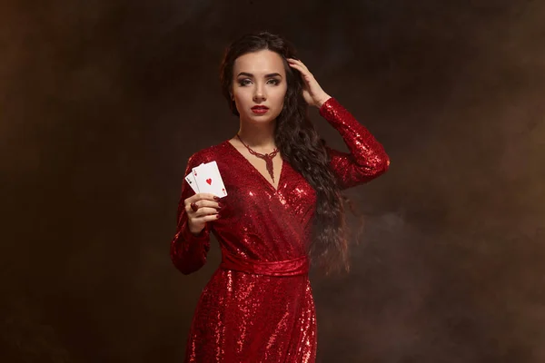 Mladá krásná štěstí brunetka v červené večerní šaty ukazuje její karty, dvojice aces — Stock fotografie