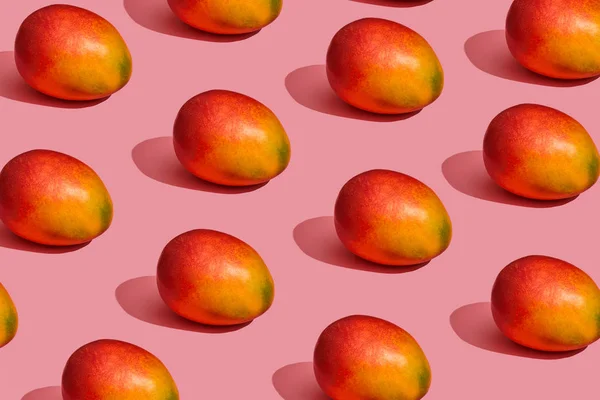 Pattern composition of a sweet tasty mango lying next to a pink background , top view