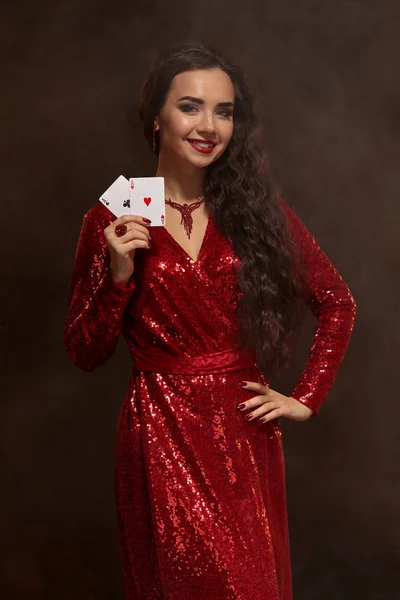 Mladá krásná štěstí brunetka v červené večerní šaty ukazuje její karty, dvojice aces — Stock fotografie