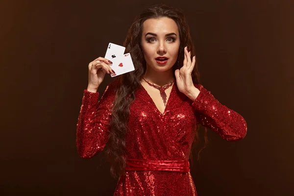 Giovane bella bruna fortunata in un abito da sera rosso mostra le sue carte, un paio di assi — Foto Stock
