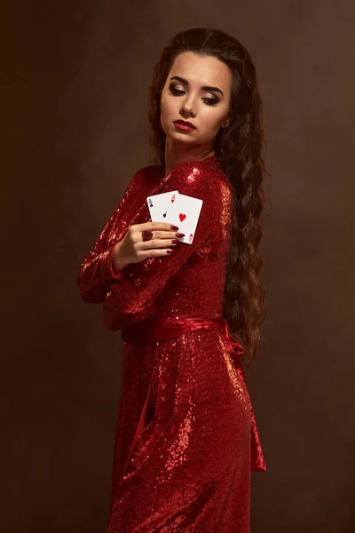 Joven morena hermosa suerte en un vestido de noche rojo muestra sus tarjetas, un par de ases — Foto de Stock