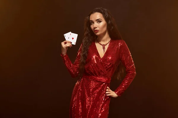Giovane bella bruna fortunata in un abito da sera rosso mostra le sue carte, un paio di assi — Foto Stock