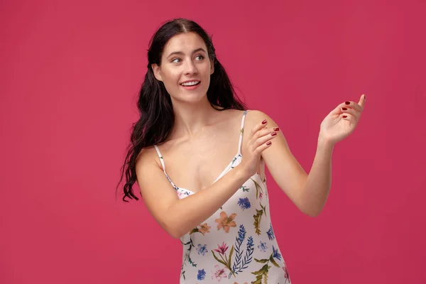 Retrato de uma jovem bonita em um vestido leve de pé sobre fundo rosa em estúdio. Pessoas emoções sinceras . — Fotografia de Stock