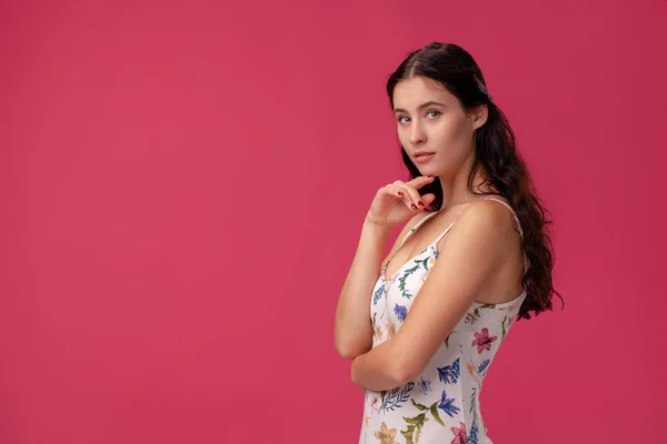 Portret van een mooie jonge vrouw in een lichte jurk staande op roze achtergrond in Studio. Mensen oprechte emoties. — Stockfoto