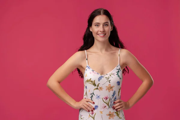 Retrato de una hermosa joven con un vestido ligero de pie sobre fondo rosa en el estudio. Personas emociones sinceras . — Foto de Stock