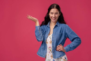 Stüdyoda pembe arka plan üzerinde duran açık bir elbise ve mavi gömlek güzel bir genç kadının portresi. İnsanlar samimi duygular.