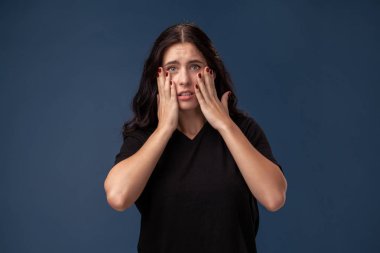 Siyah t-shirt gri bir arka plan üzerinde poz ve farklı duygular gösteren uzun saçlı esmer kadın Portresi.