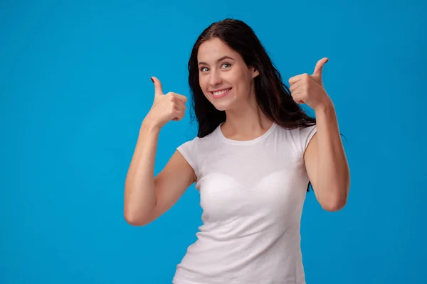 Sorrindo mulher dando polegares no fundo azul — Fotografia de Stock