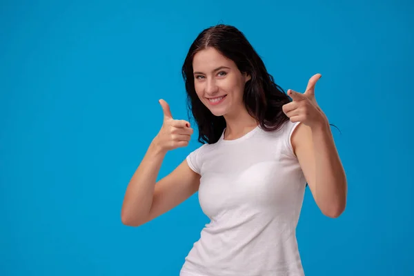 Sorrindo mulher dando polegares no fundo azul — Fotografia de Stock