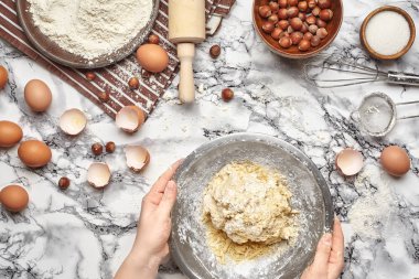 Yakın çekim. Bir fırıncı yemek yeri üst görünümü, eller mermer masa arka plan üzerinde ham bir hamur ile çalışıyoruz.