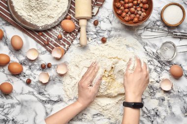 Yakın çekim. Bir fırıncı yemek yeri üst görünümü, eller mermer masa arka plan üzerinde ham bir hamur ile çalışıyoruz.
