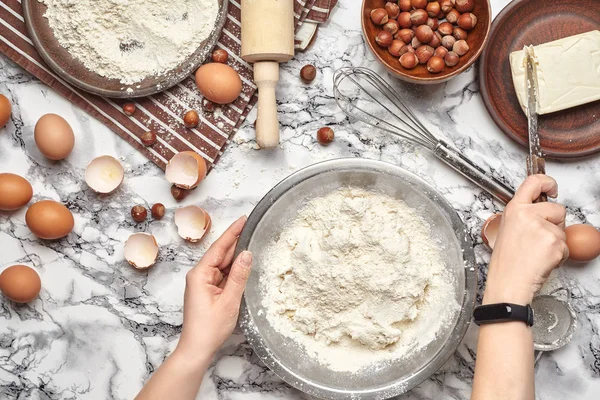 Um plano de perto. Vista superior de um local de cozinheira padeiro, as mãos estão trabalhando com uma massa crua no fundo da mesa de mármore . — Fotografia de Stock