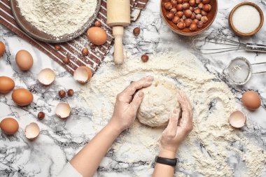 Yakın çekim. Bir fırıncı yemek yeri üst görünümü, eller mermer masa arka plan üzerinde ham bir hamur ile çalışıyoruz.