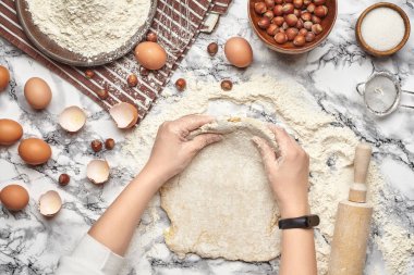 Yakın çekim. Bir fırıncı yemek yeri üst görünümü, eller mermer masa arka plan üzerinde ham bir hamur ile çalışıyoruz.