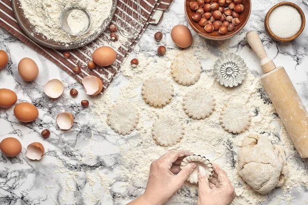 Um plano de perto. Vista superior de um local de cozinheira padeiro, as mãos estão trabalhando com uma massa crua no fundo da mesa de mármore . — Fotografia de Stock