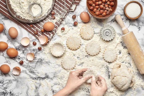 Um plano de perto. Vista superior de um local de cozinheira padeiro, as mãos estão trabalhando com uma massa crua no fundo da mesa de mármore . — Fotografia de Stock