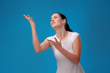 Mavi duvar arka plan karşı beyaz bir t-shirt genç bir güzel kadının Stüdyo portresi. İnsanlar samimi duygular.