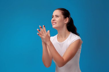 Mavi duvar arka plan karşı beyaz bir t-shirt genç bir güzel kadının Stüdyo portresi. İnsanlar samimi duygular.