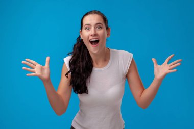 Mavi duvar arka plan karşı beyaz bir t-shirt genç bir güzel kadının Stüdyo portresi. İnsanlar samimi duygular.