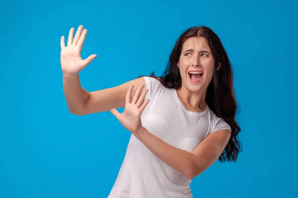 Retrato de estudio de una joven hermosa mujer con una camiseta blanca sobre un fondo de pared azul. Personas emociones sinceras . —  Fotos de Stock