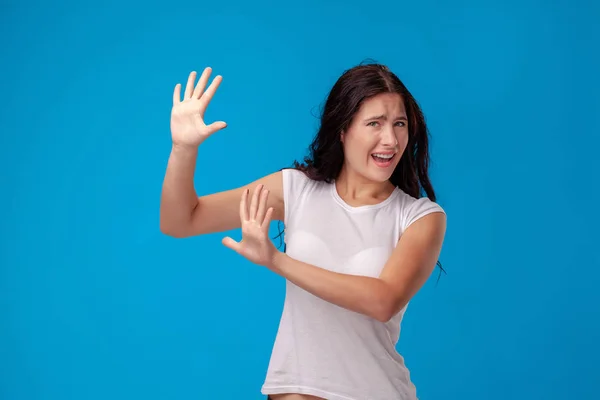 Retrato de estudio de una joven hermosa mujer con una camiseta blanca sobre un fondo de pared azul. Personas emociones sinceras . —  Fotos de Stock