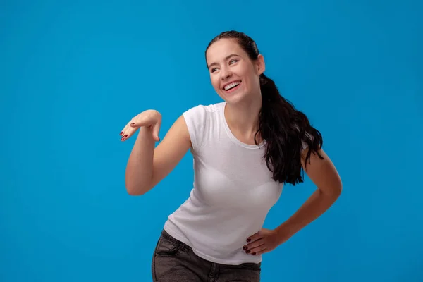 Studioporträt einer jungen schönen Frau in weißem T-Shirt vor blauem Hintergrund. Menschen aufrichtige Emotionen. — Stockfoto