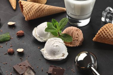 Gurme kremalı ve çikolatalı dondurma siyah bir arka plan üzerinde bir taş kayrak üzerinde servis.