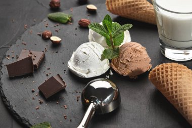 Gurme kremalı ve çikolatalı dondurma siyah bir arka plan üzerinde bir taş kayrak üzerinde servis.