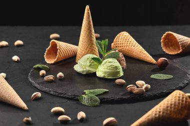 Gurme çikolata ve antep fıstığı dondurma siyah bir arka plan üzerinde bir taş kayrak üzerinde servis.