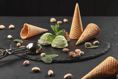 Gurme çikolata ve antep fıstığı dondurma siyah bir arka plan üzerinde bir taş kayrak üzerinde servis.