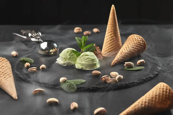 Gourmet chocolate and pistachio ice cream served on a stone slate over a black background. — Stock Photo, Image