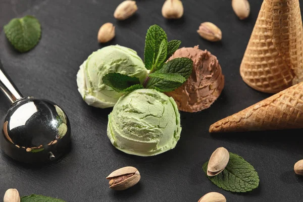 Gurme çikolata ve antep fıstığı dondurma siyah bir arka plan üzerinde bir taş kayrak üzerinde servis.