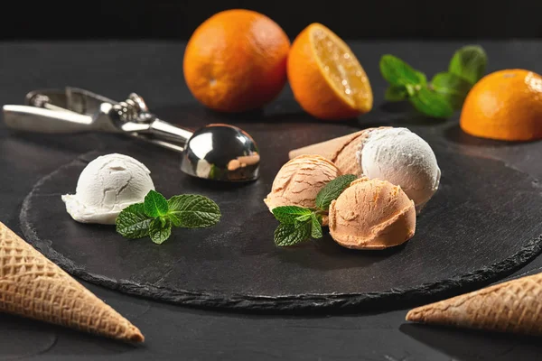 Primer plano de un helado cremoso y naranja servido sobre un fondo negro de pizarra oscura . —  Fotos de Stock