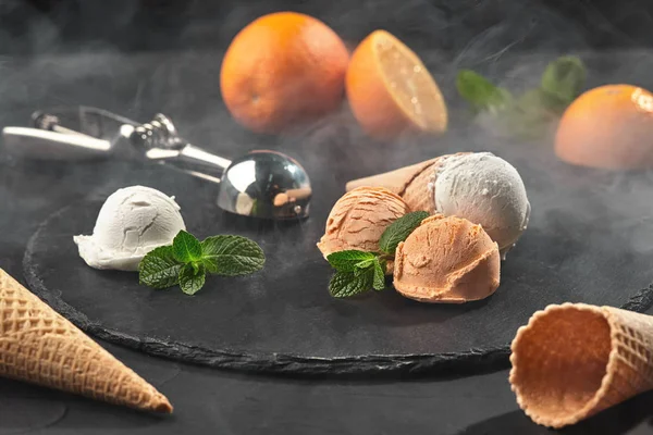 Primer plano de un helado cremoso y naranja servido sobre un fondo negro de pizarra oscura . — Foto de Stock