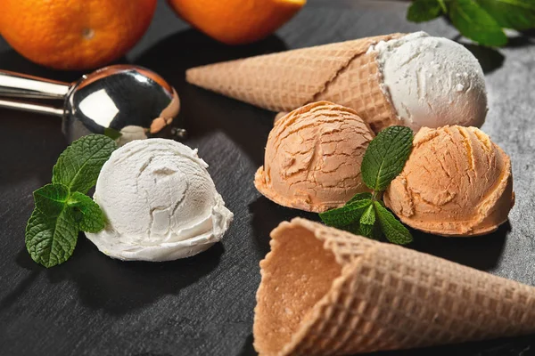 Close-up shot of a creamy and orange ice cream served on a dark slate, black background. — Stock Photo, Image