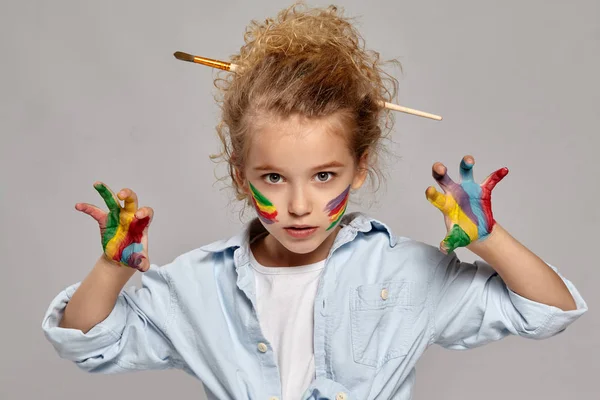 Красивая маленькая девочка с раскрашенными пальцами позирует на сером фоне . — стоковое фото