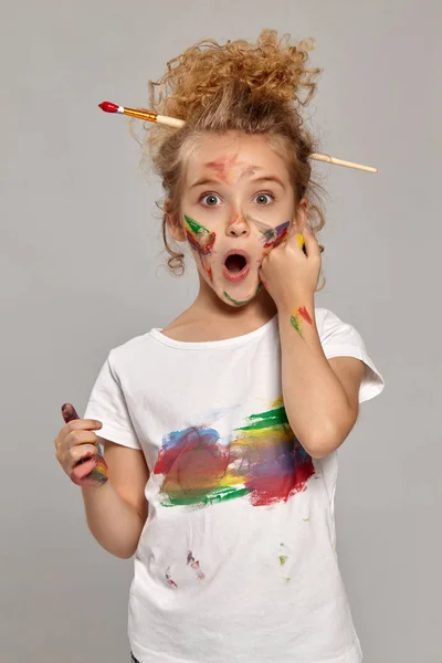 Mooi klein meisje met een geschilderde vingers poseren op een grijze achtergrond. — Stockfoto