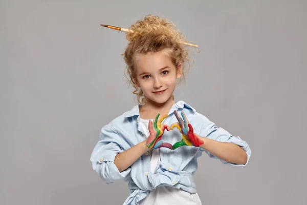 Menina bonita com as mãos pintadas está posando em um fundo cinza . — Fotografia de Stock