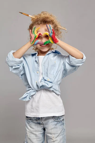 Mooi klein meisje met een geschilderde handen poseren op een grijze achtergrond. — Stockfoto