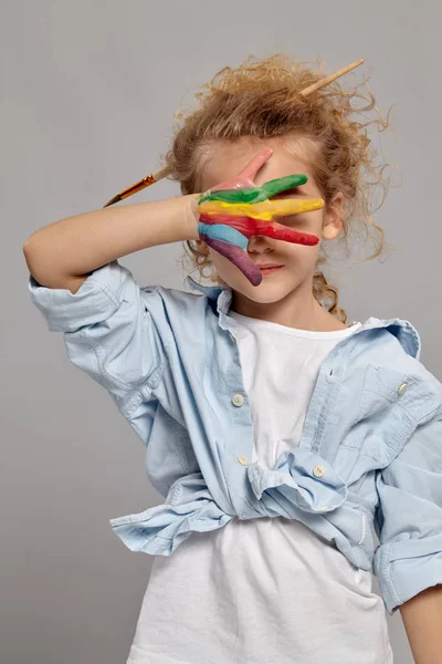 Menina bonita com as mãos pintadas está posando em um fundo cinza . — Fotografia de Stock