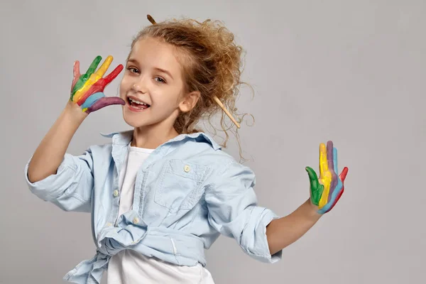 Menina bonita com as mãos pintadas está posando em um fundo cinza . — Fotografia de Stock