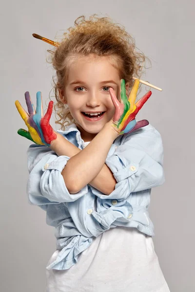 Beautiful little girl with a painted hands is posing on a gray background. — Stock Photo, Image