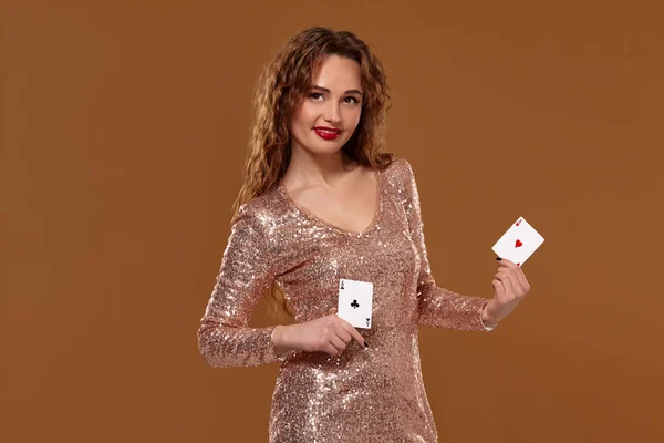 金发女子穿着金色闪闪发光的连衣裙，手里拿着两张扑克牌。赌场. — 图库照片