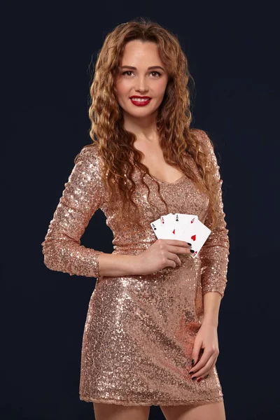 Bella giovane donna emotiva in abito da cocktail mostrando le sue carte all'avversario, quattro di assi, migliore mano. sfondo Blcak, ripresa in studio — Foto Stock