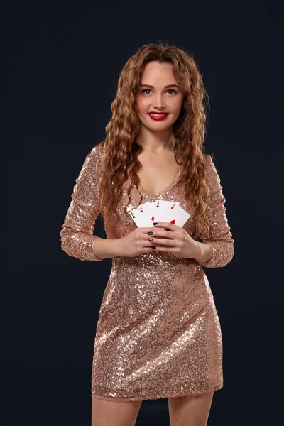 Krásná mladá citová žena v koktejlových šatech zobrazující karty soupeři, čtyři esa, nejlepší ruka. Blcakovo pozadí, snímek studia — Stock fotografie