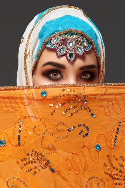 Payet ve takıile süslenmiş renkli başörtüsü giyen bir chrming kadın Stüdyo çekim. Arap tarzı.