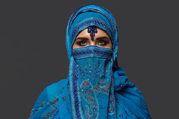 Studio shot van een jonge mooie vrouw het dragen van de blauwe hijab versierd met pailletten en sieraden. Arabische stijl. — Stockfoto