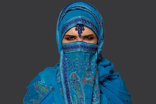 Studiová střela mladé ženy v modrém hidžábu ozdobená sekernami a šperky. Arabský styl. — Stock fotografie