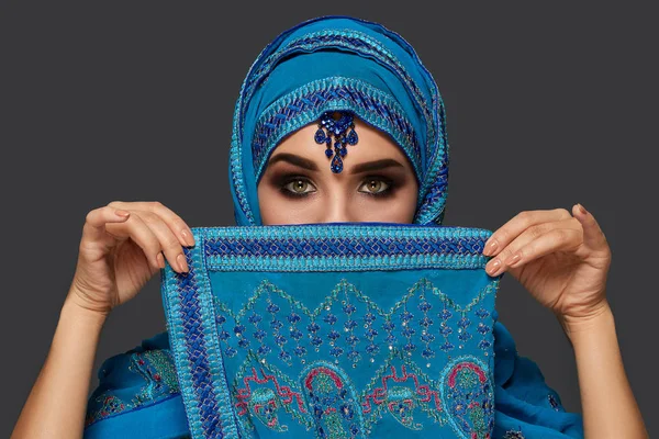 Студийный снимок молодой красивой женщины в синем хиджабе, украшенном блестками и украшениями. Арабский стиль . — стоковое фото