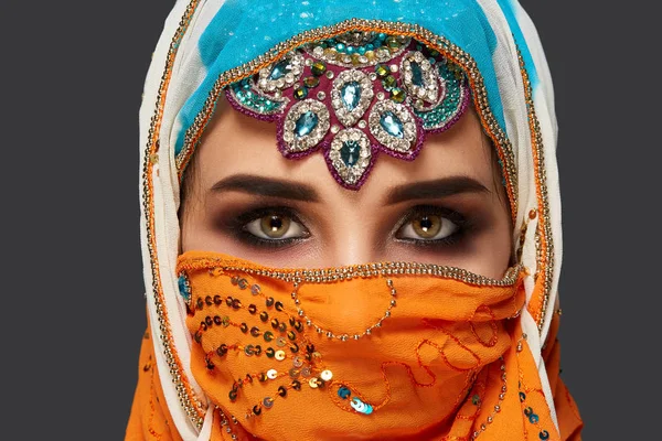 Studio shot van een chrming vrouw het dragen van de kleurrijke hijab versierd met pailletten en sieraden. Arabische stijl. — Stockfoto